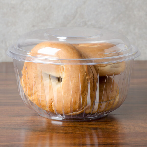 A Dart clear plastic bowl with a dome lid containing bagels.