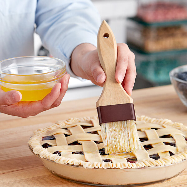 A person using a Vollrath boar bristle pastry brush to paint a pie.