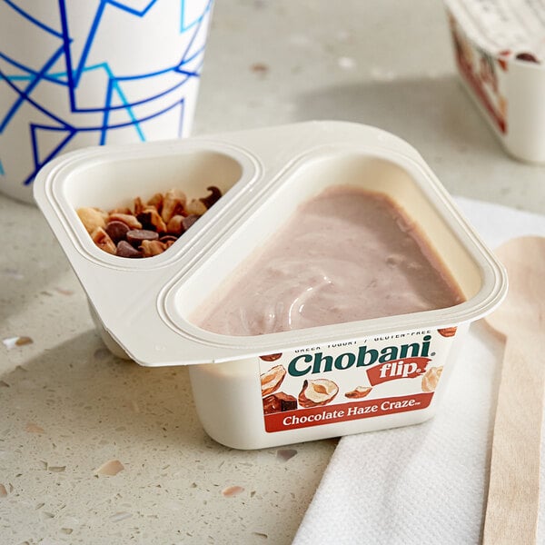 A cup of Chobani Flip Chocolate Haze Craze Low-Fat Chocolate Hazelnut Greek Yogurt with a blue spoon.