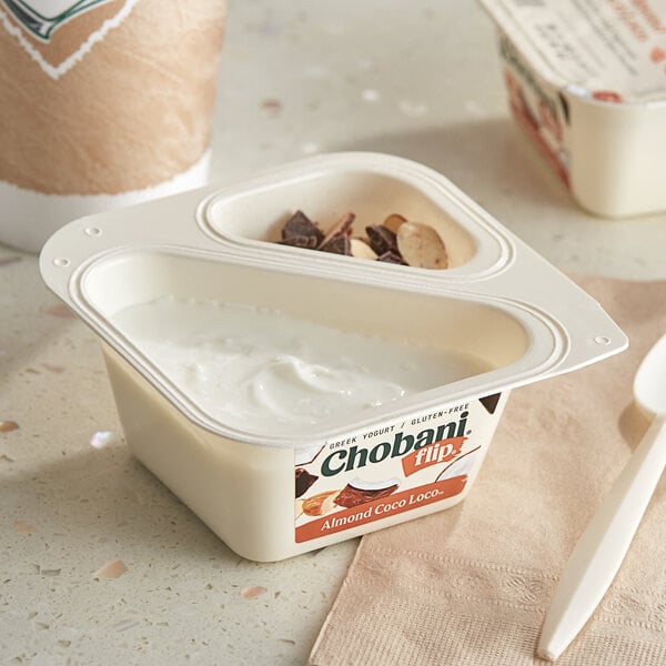 A white Chobani Flip Low-Fat Coconut Greek Yogurt container with a white lid and a spoon.