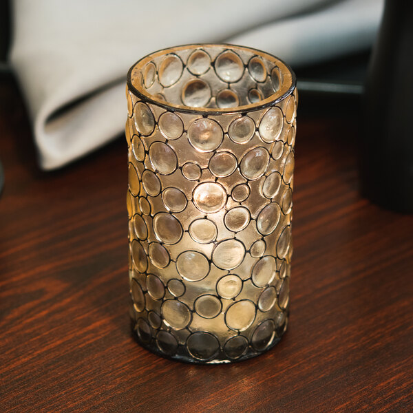 A Sterno resin bubble candle holder with a lit candle on a table.