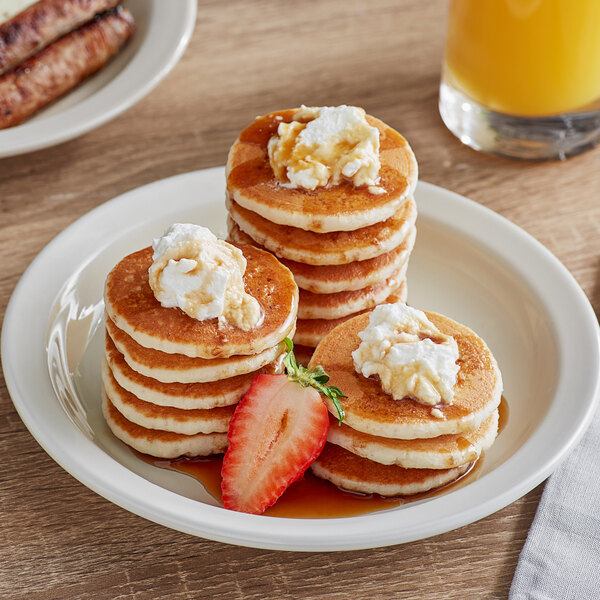 A plate of Krusteaz mini pancakes with butter, syrup, and strawberries.