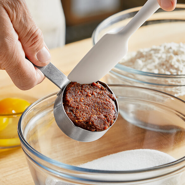 A person using a measuring spoon to scoop out Date Lady Organic Date Paste.