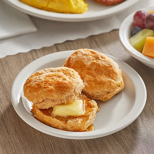 A white plate with Bakery Chef Buttermilk Biscuits and fruit.