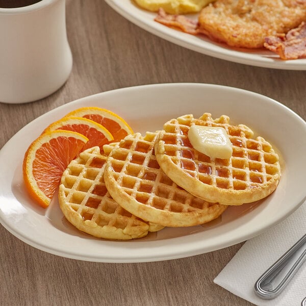 A plate with Krusteaz waffles and orange slices on it.