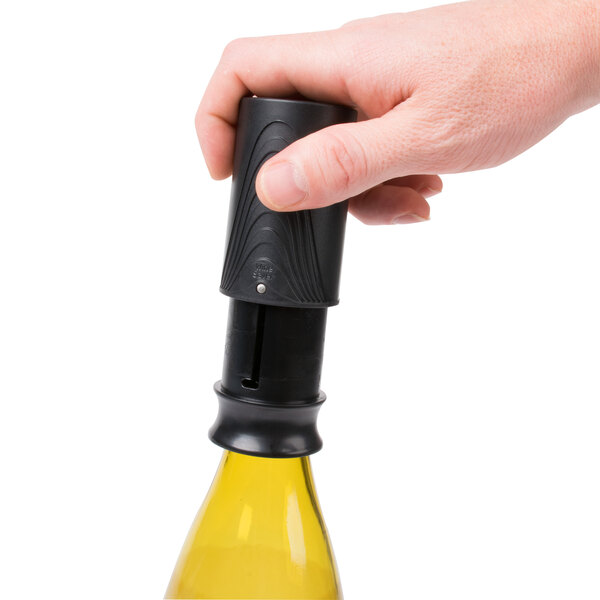 A hand holding a Franmara black wine saver vacuum pump bottle stopper over a wine bottle.
