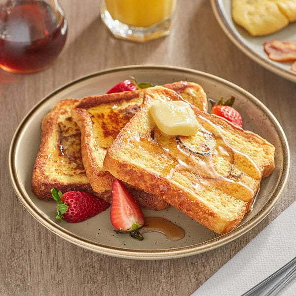 A plate of Krusteaz Cinnamon Swirl French Toast with butter and strawberries on top.