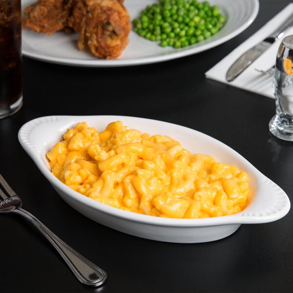 A Tuxton white oval china rarebit with macaroni and cheese on a table.