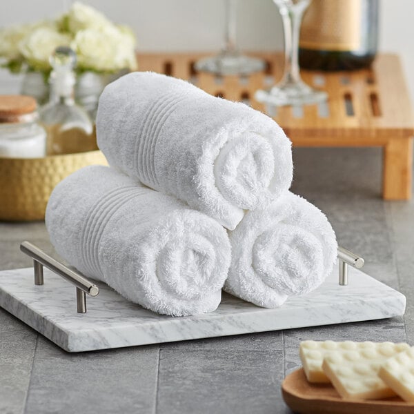 A stack of three white Lavex Luxury hand towels on a tray.