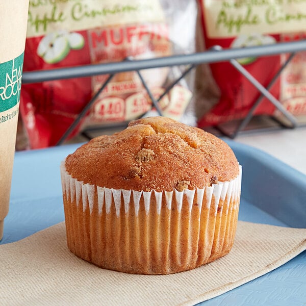 An Otis Spunkmeyer apple cinnamon muffin in a paper wrapper on a napkin.