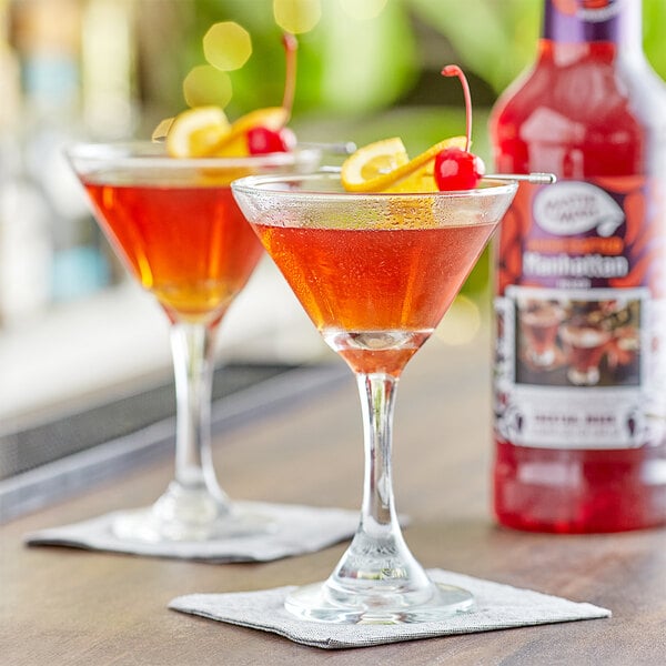 A pair of glasses with Manhattan Martini made with Master of Mixes Manhattan Martini Mix, garnished with cherries.