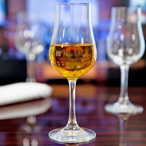 A Stolzle Euro Brandy glass filled with yellow liquid on a table.