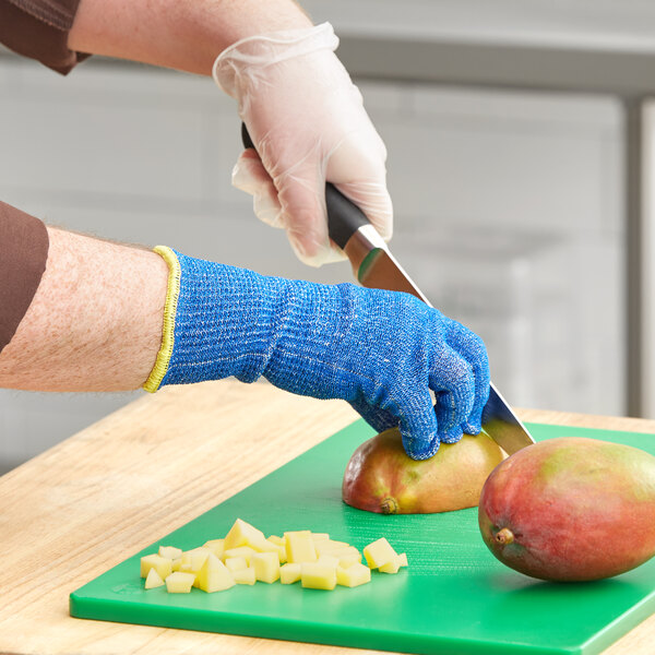 A person wearing blue Ansell HyFlex gloves peeling a mango.