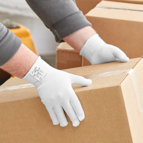 A person wearing Ansell white ActivArmr glove liners holding a box.
