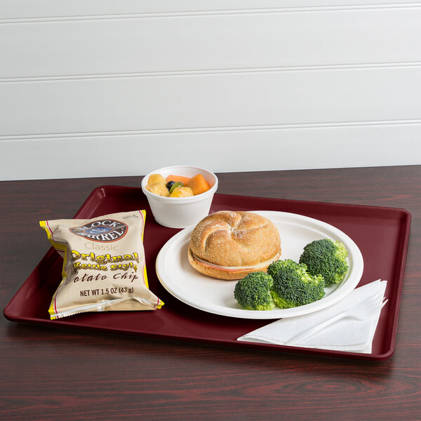 A Cambro burgundy dietary tray with a sandwich, broccoli, and chips.