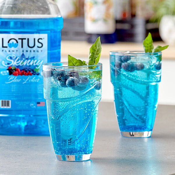 A glass of blue Lotus Plant Energy concentrate with berries and mint.