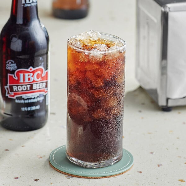 A glass of brown liquid with ice next to a bottle of IBC Root Beer.