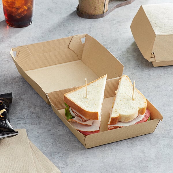 A sandwich in a Sabert Square corrugated kraft paper take-out box with a toothpick in it.