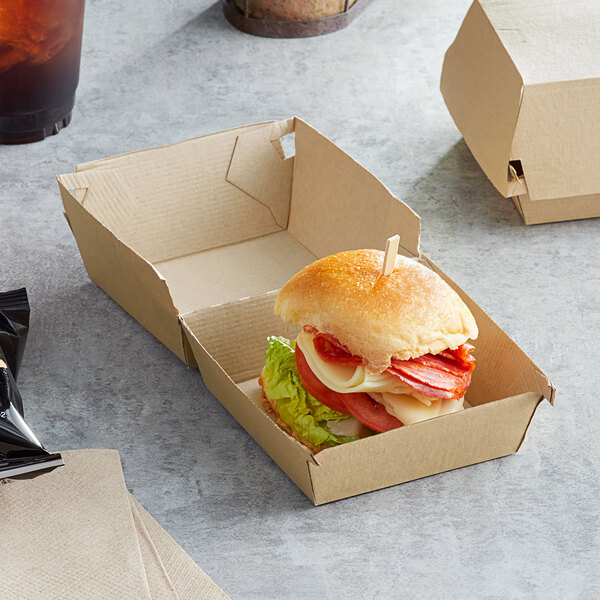 A sandwich in a Sabert paper take-out box with a drink.