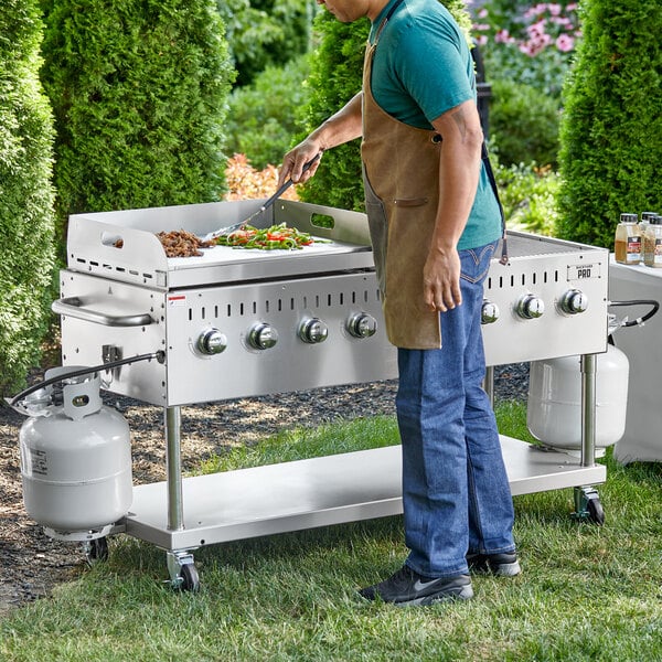 A man cooking food on a Backyard Pro stainless steel outdoor griddle.
