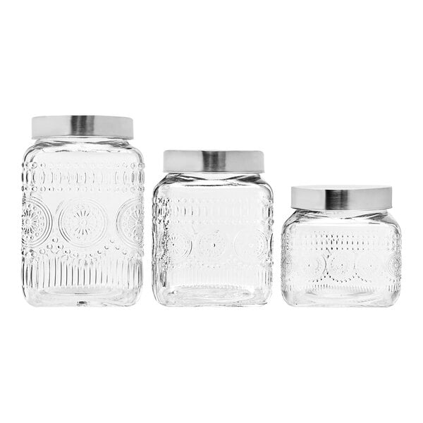 A group of clear glass Stylesetter canisters with silver lids.