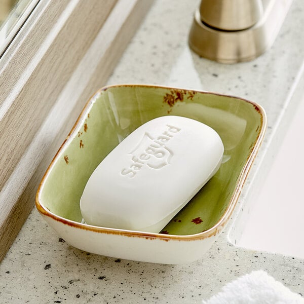 A white Safeguard Aloe bar soap in a green dish on a counter.