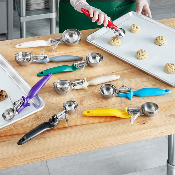 A woman using a red Choice Ergonomic Thumb Press Disher to measure cookie dough on a table.