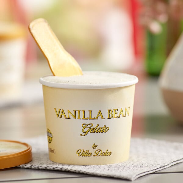 A Villa Dolce Vanilla Bean Gelato cup with a wooden spoon inside.