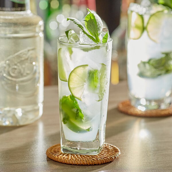 A glass of water with ice, lime slices, and mint leaves.
