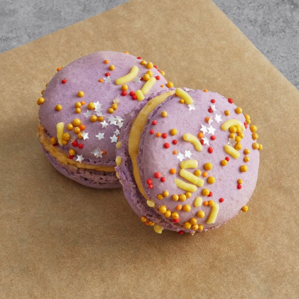 Two purple Macaron Centrale macarons with sprinkles on them.