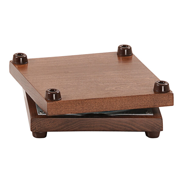 A wooden square Cal-Mil rotating display base with screws on a table.