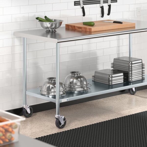 A Steelton stainless steel work table with casters and an undershelf holding bowls and a cutting board.