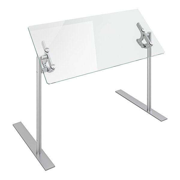 A Spring USA glass food shield on a table with metal legs.