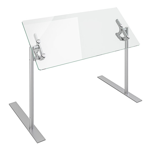 A clear glass Spring USA Versa-Gard portable adjustable food shield on a table with silver metal legs.