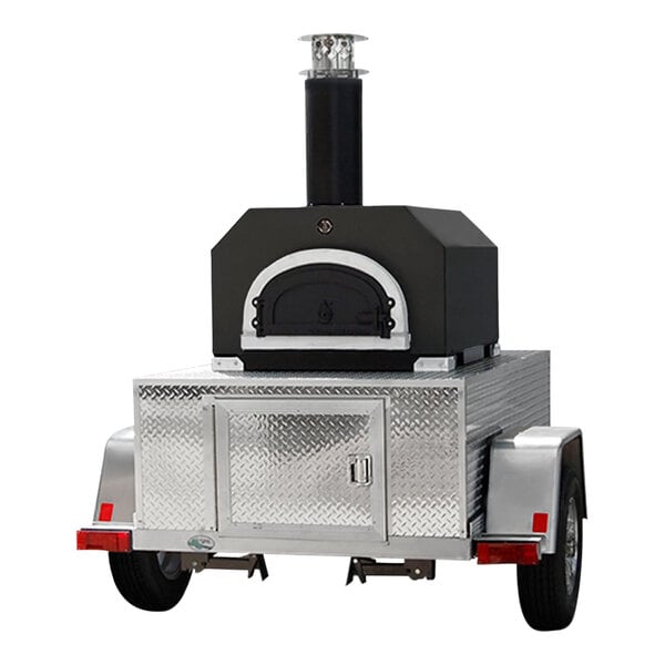 A black and silver Chicago Brick Oven Tailgater wood-fired pizza oven on a trailer.
