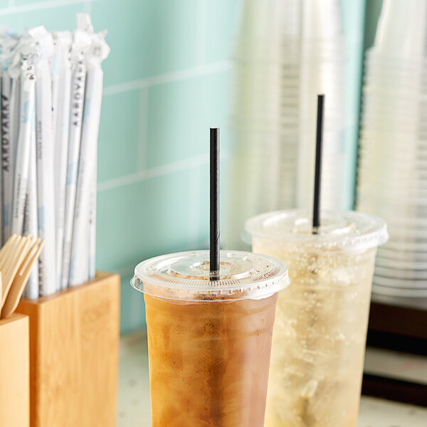 A couple of plastic cups with Aardvark black paper straws and brown liquid.