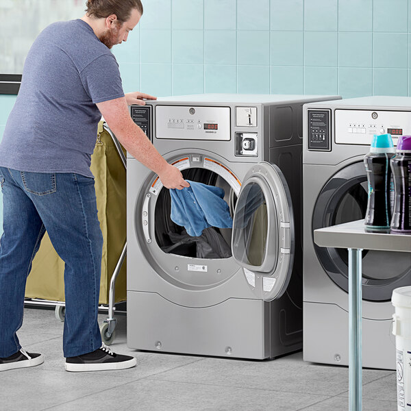A man putting a blue shirt into a Crossover commercial dryer.