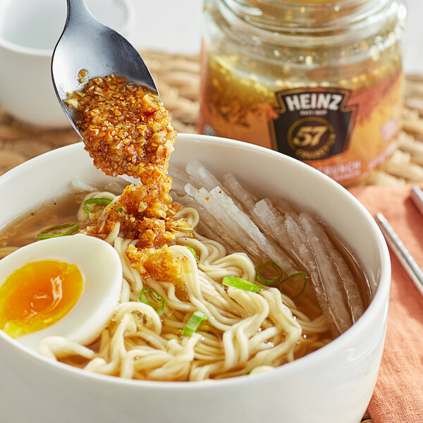 A spoonful of Heinz 57 Roasted Garlic Culinary Crunch sauce in a bowl of ramen.