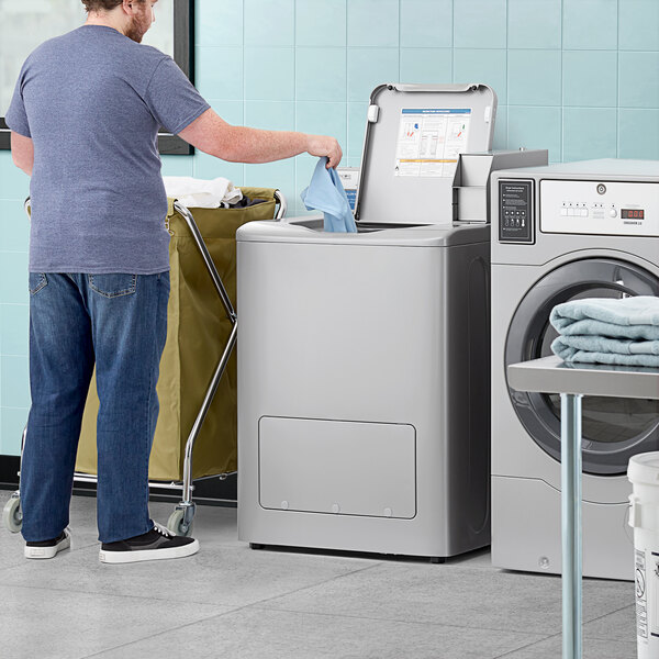 A man standing next to a commercial laundry machine.