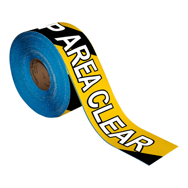 A roll of black and yellow striped Superior Mark safety tape with the words "Keep Area Clear" on it.