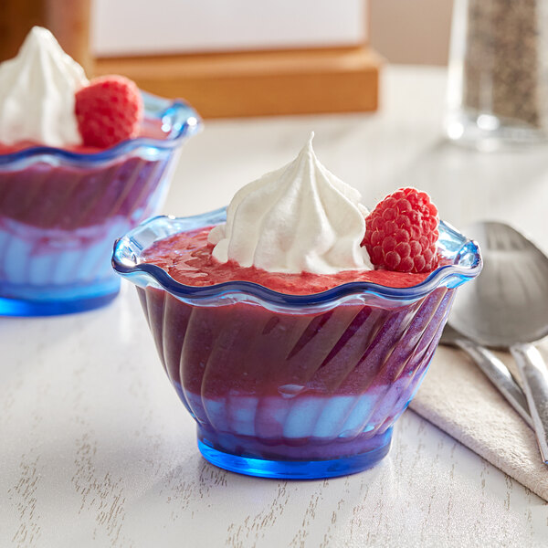 A blue plastic dessert dish filled with white dessert and raspberries with whipped cream.