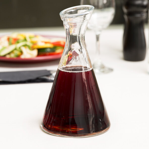 A Stolzle Pisa carafe filled with red liquid on a table in an Italian restaurant.