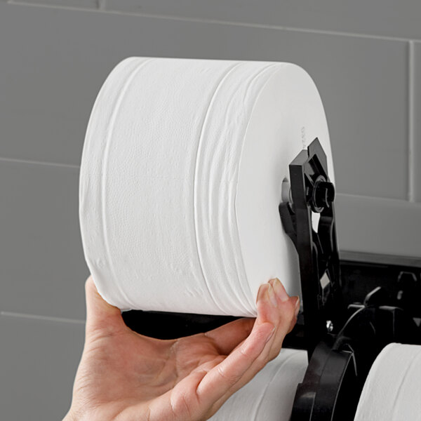 A hand holding a roll of Angel Soft Professional Series Compact toilet paper.