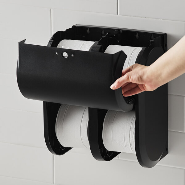 A hand pulling a roll of Compact by GP Pro toilet paper into a dispenser.