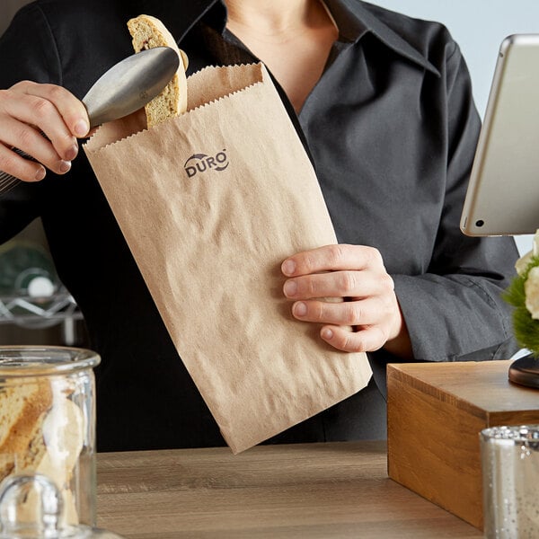 A woman holding a Duro brown merchandise bag of food with a spoon.