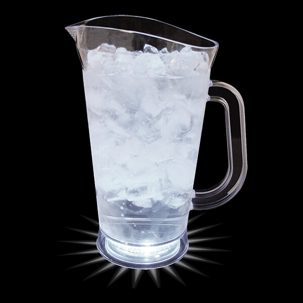 A clear plastic pitcher with ice and water in it.