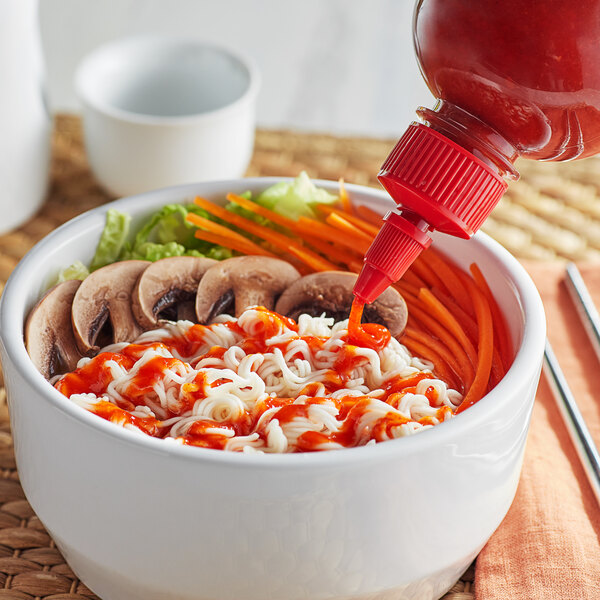 A bowl of noodles with vegetables and Pride O' Thai Sriracha Sauce.