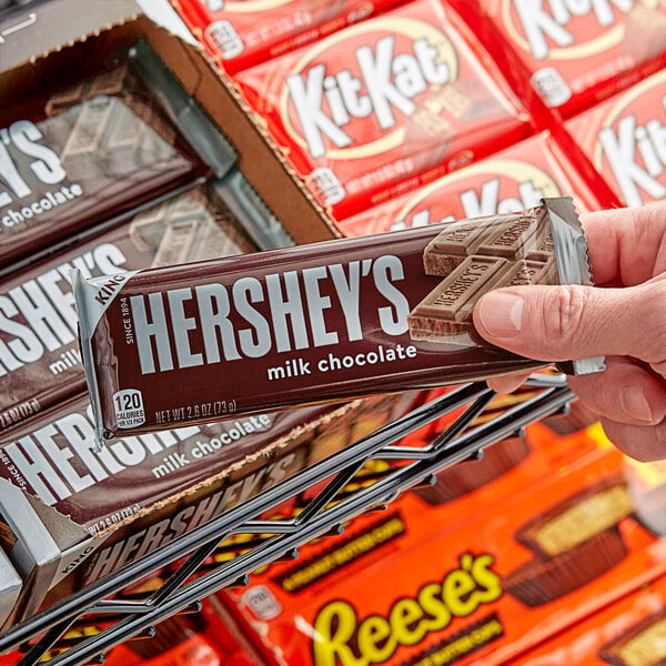 A hand holding a HERSHEY'S King Size Milk Chocolate bar.