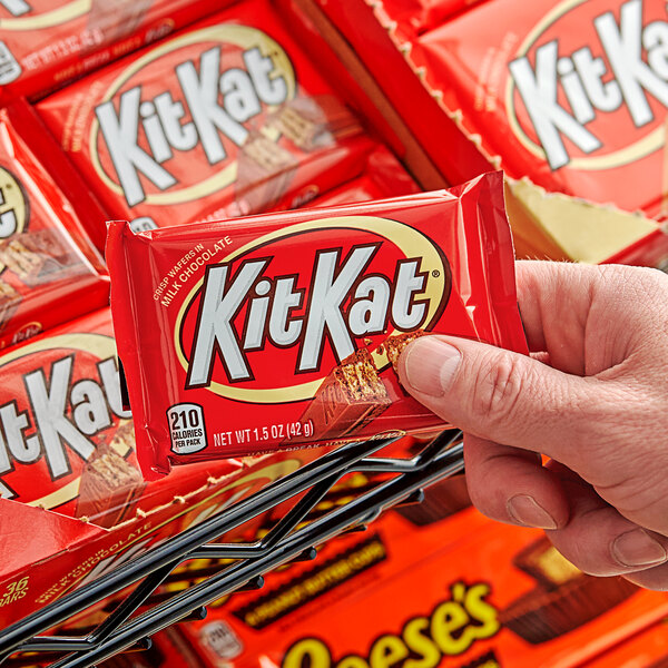 A hand holding a KIT KAT Milk Chocolate Bar.