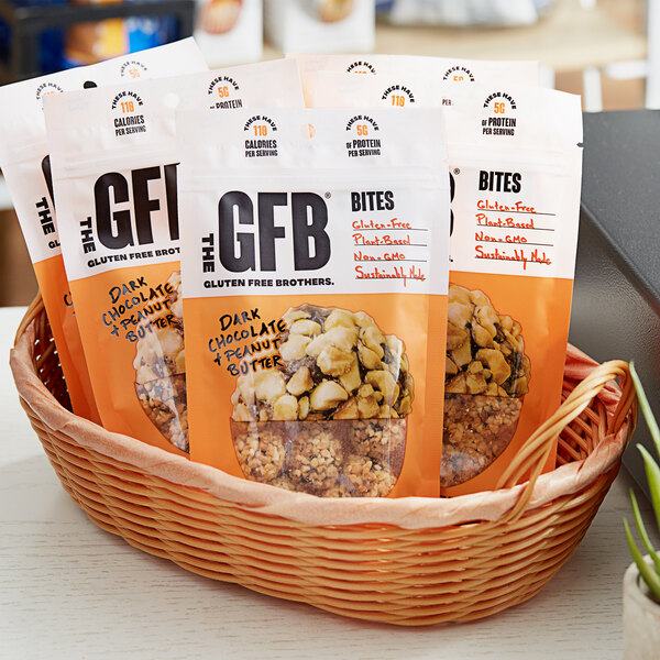 A basket filled with bags of The GFB Dark Chocolate Peanut Butter Bites on a table.